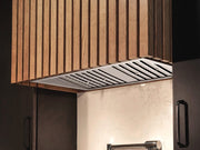 VICTORY Q2 stainless steel range hood insert installed in a custom wood-slat enclosure, highlighting its slim design and integrated kitchen lighting