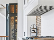 Victory Q5 range hood insert seamlessly integrated into a luxury custom kitchen with white cabinetry and industrial brick accents