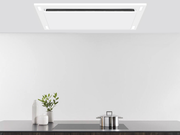 Matte white VICTORY Sunset range hood installed in a custom ceiling soffit box over a black induction cooktop, highlighting the perimeter suction panel and built-in LED lighting.