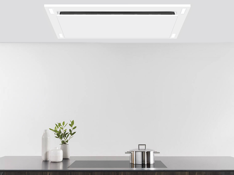 Matte white VICTORY Sunset range hood installed in a custom ceiling soffit box over a black induction cooktop, highlighting the perimeter suction panel and built-in LED lighting.