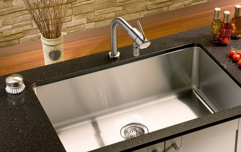 Top-down view of a rectangular stainless steel sink bottom protector grid featuring a center drain cutout and black protective rubber bumpers.